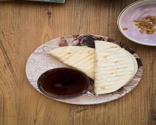 A healthy Pakistani breakfast consisting of an omelet, flatbread, and a cup of tea