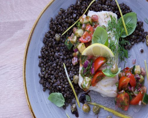 A lunch plate with cooked lentils, white rice, and fresh cucumber and tomato salad
